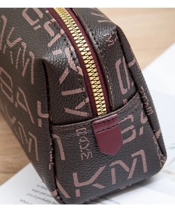 Close-up of brown textured leather coin purse with KM print and gold zipper detail