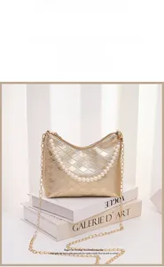 Detail der goldene Stepptasche aus Leder mit Perlengriff und Metallkettenriemen