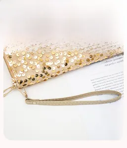 Detail of the golden sequin clutch wallet featuring a detachable wristlet strap