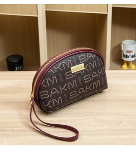Vue détaillée de la pochette SAKM avec motif lettres et plaque dorée élégante