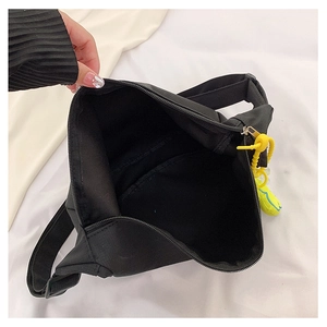 Détail du sac bandoulière en nylon noir avec grand compartiment et pendentif vert néon