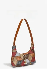 Detail of color-block shoulder bag featuring crocodile textures and pearl bead charms