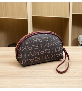Détail macro de la pochette semi-circulaire avec imprimé SAKM et dragonne bordeaux