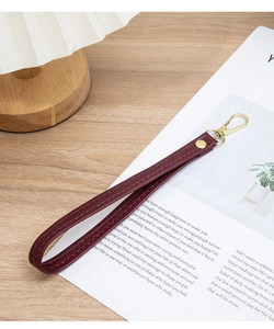 Detail of burgundy leather wrist strap with golden metal lobster clasp and vintage stitching