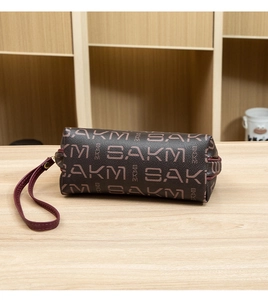 Vue détaillée de l'imprimé SAKM sur la trousse de toilette cylindrique marron