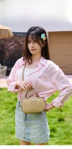 Modella all'aperto con borsa a tracolla intrecciata beige e dettagli in metallo dorato
