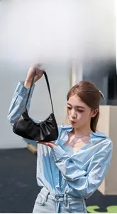 Detail of black pleated cloud shoulder bag with premium leather texture on a female model