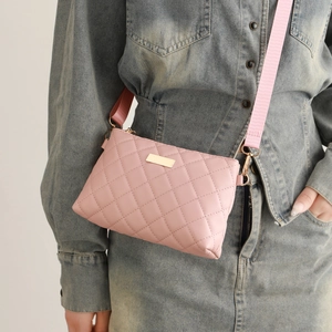 Detailed shot of pink quilted crossbody bag with gold hardware and wide fabric strap