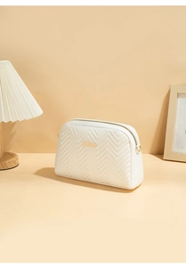 Detail of white quilted PU leather makeup bag with gold zipper and metal logo plate