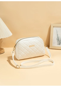 Detail of beige quilted faux leather crossbody bag with golden zipper and metal plate