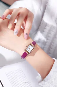 Details der eleganten rechteckigen Roségold-Uhr mit lila Lederarmband am Handgelenk
