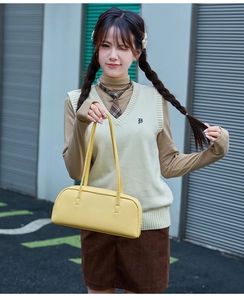 Gros plan d'un sac baguette jaune à fines bretelles sur un fond urbain moderne