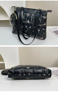 Detail of black PU leather tote bag with pink floral embroidery and matching pouch