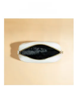 Interior view of white quilted crossbody bag with gold zipper showing black lining