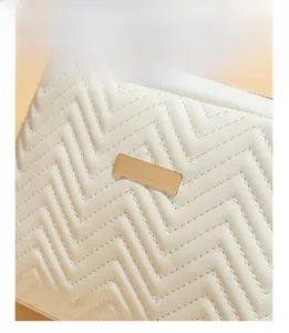 Detail of white wave quilted pattern and rectangular gold metal hardware on crossbody bag