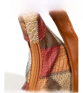 Close-up of contrast color patchwork leather bag with double stitching and metal zipper detail