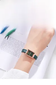 Details einer roségoldenen Rechteck-Uhr mit grünem Lederarmband und schlichtem Zifferblatt