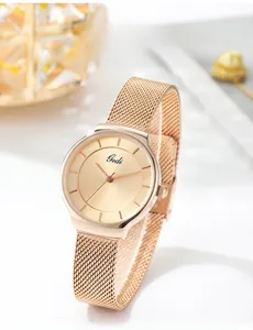Gros plan d'une montre à quartz minimaliste en or rose avec bracelet en maille milanaise
