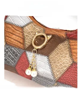 Detail of patchwork leather bag featuring exotic textures and pearl tassel charm