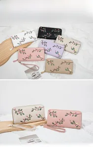 Close-up of floral embroidery on leather zipper wallets with a detachable wrist strap
