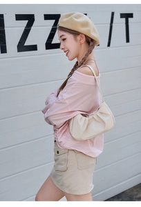 Detailed view of cream-colored pleated cloud bag with elegant shoulder strap detail