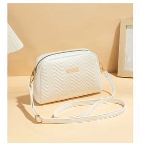 Detail of white quilted crossbody bag featuring wave texture and golden zipper hardware