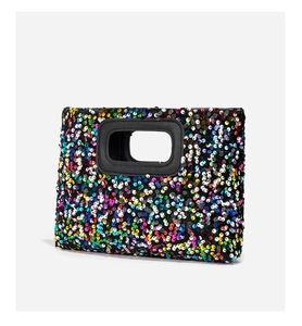 Close-up of colorful sequin handbag with unique rectangular cutout handle and black trim
