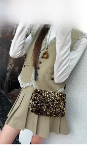 Detail of high-density gold and black sequins on a compact shoulder bag with a slim strap
