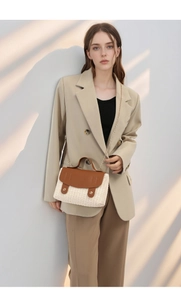 Detail of woven crossbody bag featuring cream fabric texture and brown leather flap