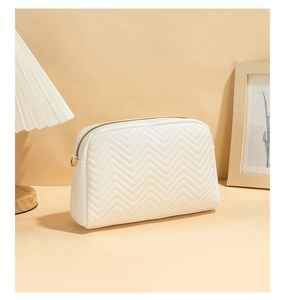 Close-up of white quilted PU crossbody bag with elegant gold zipper and wave stitching