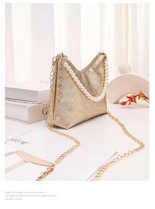 Detail der goldenen Beuteltasche mit Gitterstruktur und elegantem Perlengriff