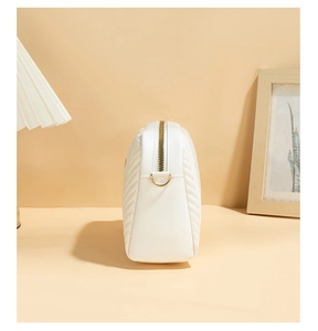 Detailed side view of white faux leather bag with V-shaped chevron quilting and gold hardware