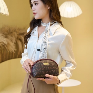 Pochette demi-cercle marron avec imprimé lettres et détails dorés dans un décor de vie