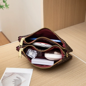 Brown monogram crossbody bag with dual zippers showing spacious interior and compartments