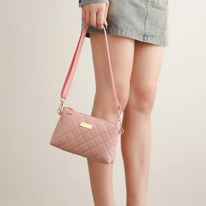 Close-up of pink quilted crossbody bag with adjustable strap and golden hardware
