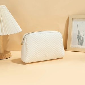 White chevron quilted camera bag with gold zipper and metal ring in a minimalist setting