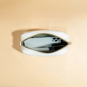 White quilted camera bag with gold zipper showing interior space for phone and cardholder