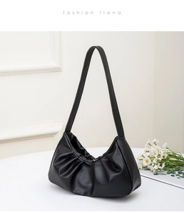 Close-up of black pleated cloud bag with textured synthetic leather and shoulder strap