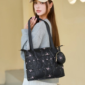 Floral embroidered satin tote bag with matching round coin purse shown on a model