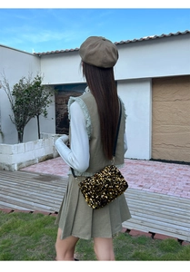 Detail of crossbody bag with dense gold and black sequins and elegant black leather strap