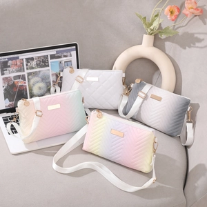 Quilted crossbody bags in white and gradient pastels displayed on a grey sofa