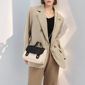 Modern woven satchel bag with black leather flap and gold chain strap shown on a model