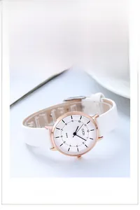 Macro detail of rose gold quartz watch with minimalist white dial and leather strap