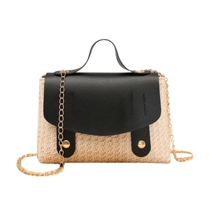 Straw woven satchel with black leather lid and gold chain strap on white background
