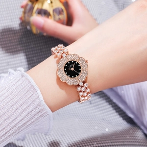 Détail d'une montre fleur en or rose avec lunette en cristal et cadran noir