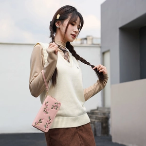 Pink long zipper clutch with floral embroidery and wristlet held by a model