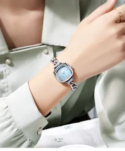Gros plan d'une montre femme avec cadran en nacre carrée et bracelet en chaîne argentée