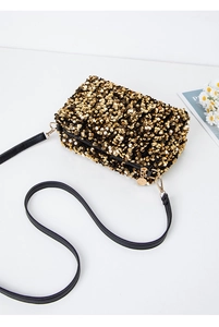 Macro detail of gold sequins on square crossbody bag with black strap and golden hardware