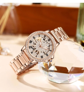 Detail of rose gold skeletal watch dial with rhinestones and blue decorated crown