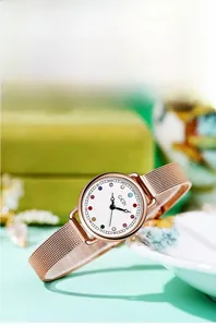 Detail of rose gold mesh watch featuring a white dial with twelve colorful birthstones